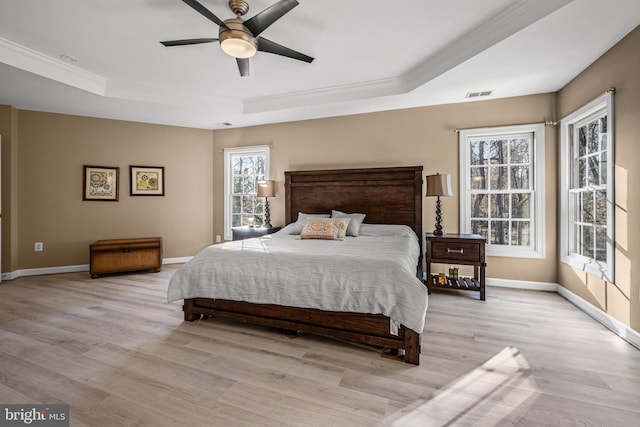 bedroom featuring visible vents, a raised ceiling, baseboards, and light wood finished floors