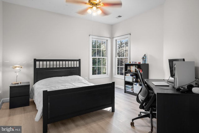 bedroom featuring light wood-style flooring, baseboards, visible vents, and ceiling fan