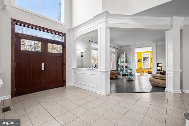 entrance foyer featuring light tile patterned flooring, a healthy amount of sunlight, and ornate columns