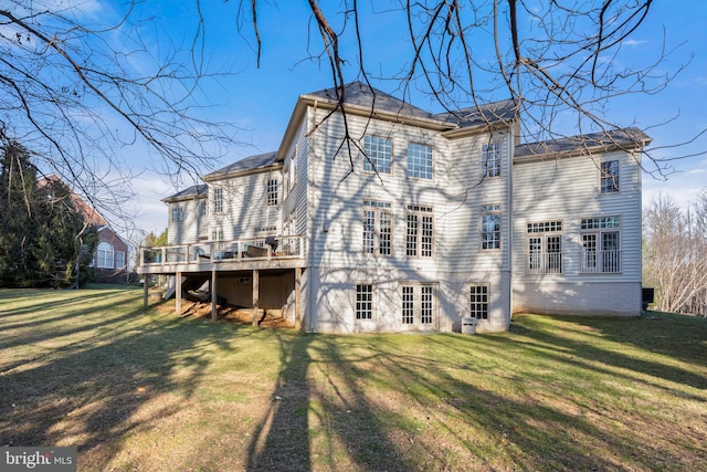 back of property featuring a wooden deck and a lawn