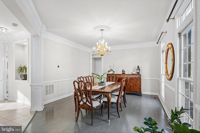 dining room featuring visible vents, baseboards, ornamental molding, an inviting chandelier, and wood finished floors