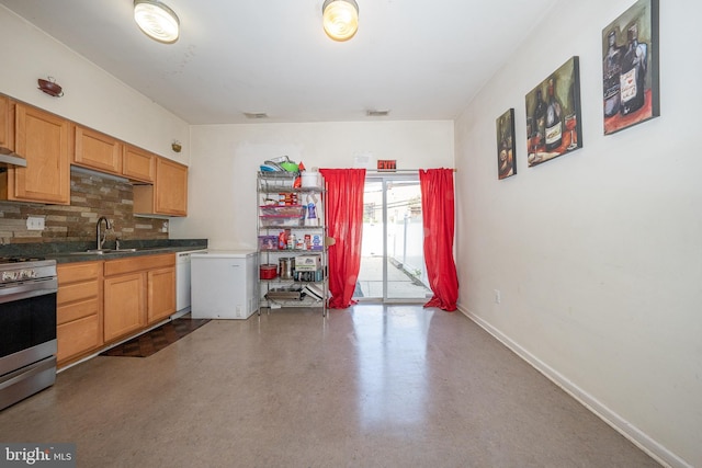 kitchen with tasteful backsplash, baseboards, stainless steel range, dark countertops, and a sink