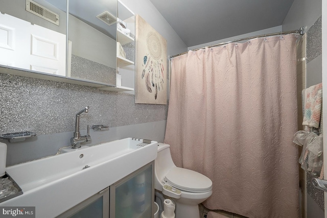 bathroom featuring toilet, vanity, and visible vents