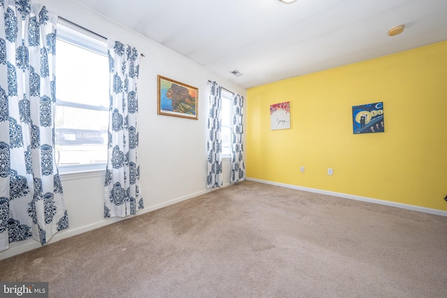 spare room featuring carpet, visible vents, and baseboards