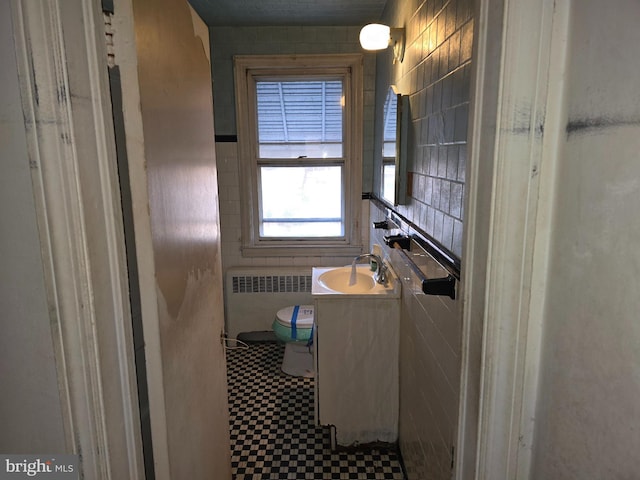 bathroom with toilet, radiator heating unit, an enclosed shower, vanity, and tile walls