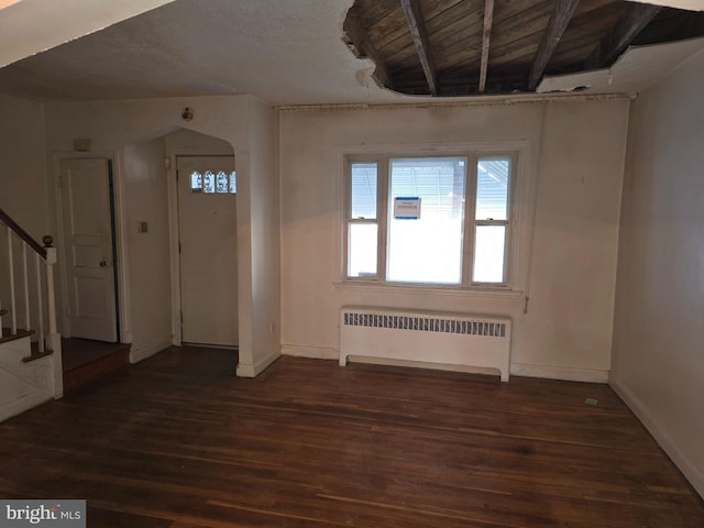 foyer with arched walkways, radiator, stairway, dark wood-type flooring, and baseboards