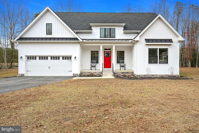 modern farmhouse style home featuring aphalt driveway, roof with shingles, covered porch, a standing seam roof, and a front lawn