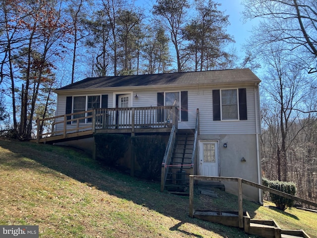 view of front facade with a front yard, stucco siding, stairs, and a wooden deck