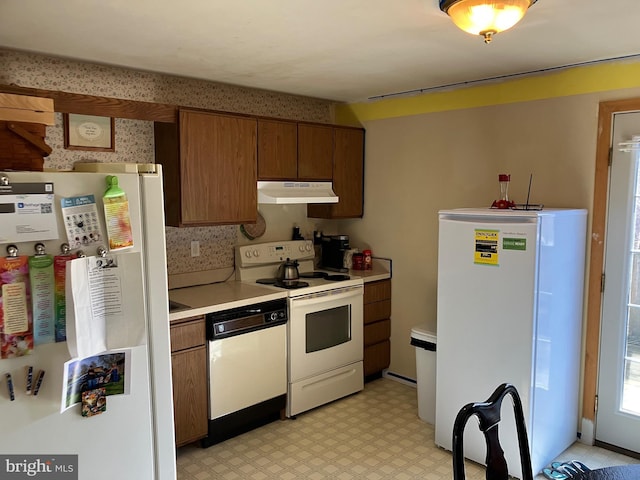 kitchen featuring light countertops, white appliances, light floors, and under cabinet range hood