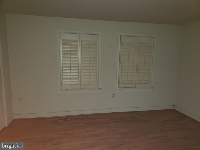 spare room with baseboards and light wood finished floors