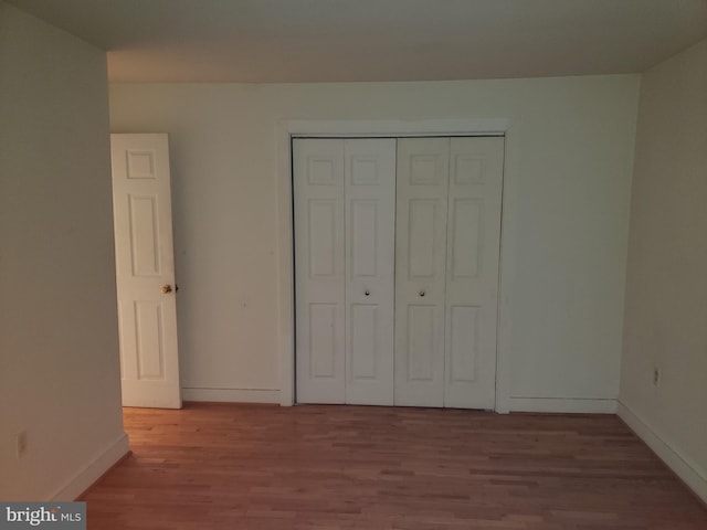 unfurnished bedroom featuring a closet, baseboards, and wood finished floors