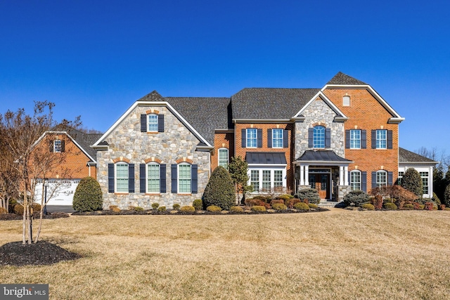 view of front of home featuring a front lawn, a standing seam roof, and brick siding