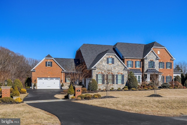 view of front of home featuring a garage, brick siding, driveway, a standing seam roof, and a front yard