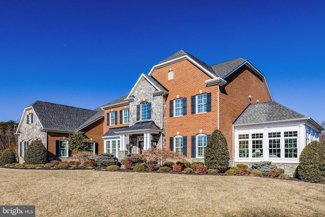 view of front facade with stone siding, brick siding, and a front yard