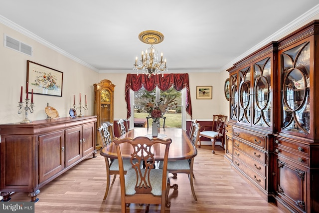 dining space with a chandelier, ornamental molding, light wood-type flooring, and visible vents