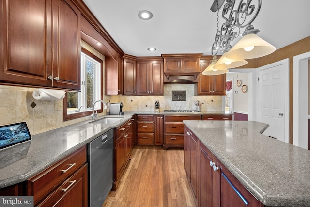 kitchen featuring light wood finished floors, a kitchen island, appliances with stainless steel finishes, pendant lighting, and a sink