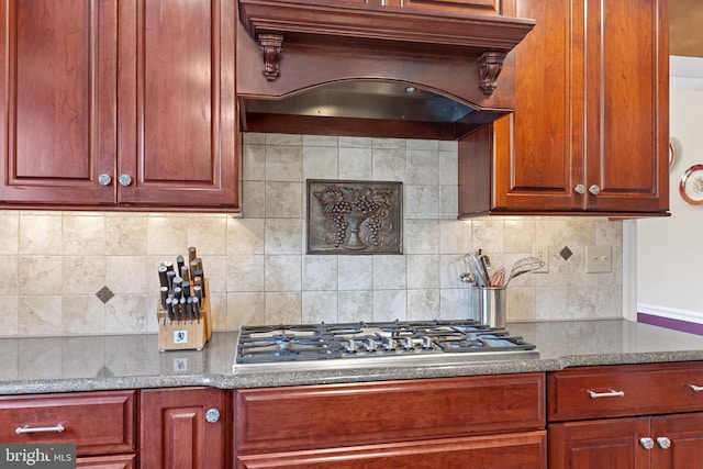 kitchen with decorative backsplash, custom range hood, dark brown cabinets, stone counters, and stainless steel gas stovetop