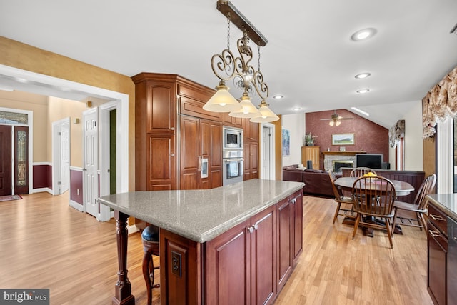 kitchen featuring a breakfast bar area, open floor plan, decorative light fixtures, a center island, and stainless steel appliances