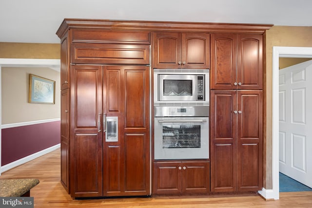 kitchen with built in appliances, light wood finished floors, and baseboards