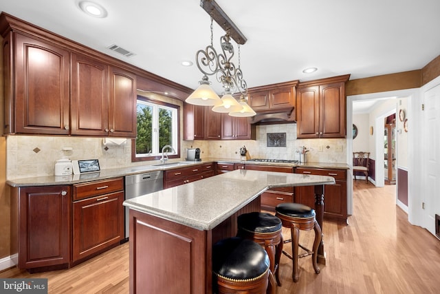 kitchen featuring visible vents, a breakfast bar, a center island, stainless steel appliances, and pendant lighting