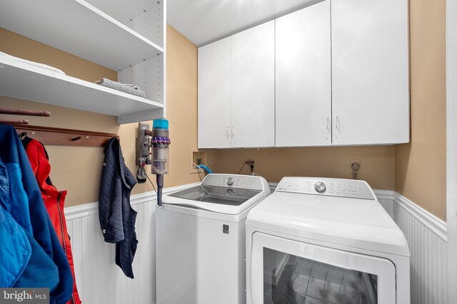 laundry area featuring wainscoting, cabinet space, and washer and dryer