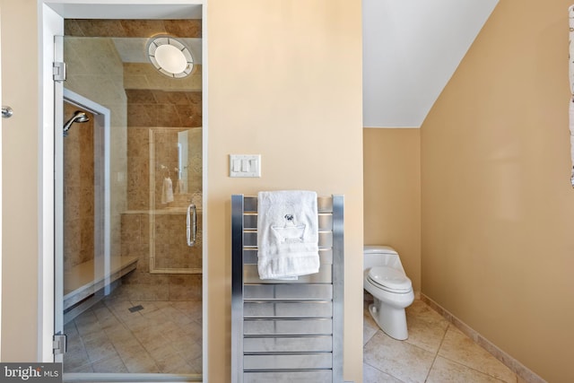 bathroom featuring a stall shower, baseboards, toilet, and tile patterned floors