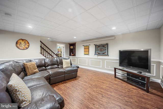 living area featuring a decorative wall, stairway, wood finished floors, and recessed lighting