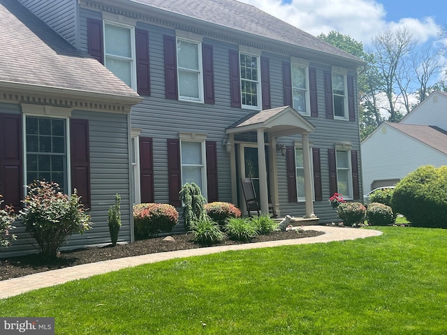 view of front of house featuring a front lawn and a shingled roof