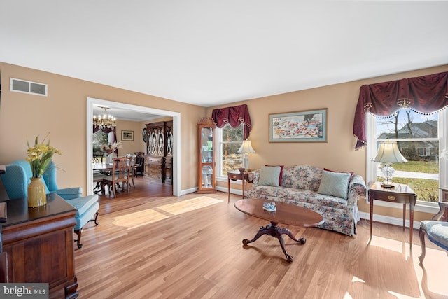 sitting room featuring light wood-type flooring, an inviting chandelier, baseboards, and visible vents