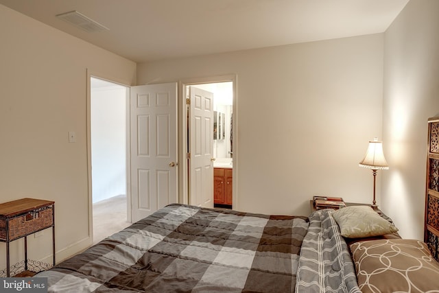 carpeted bedroom featuring visible vents and ensuite bath