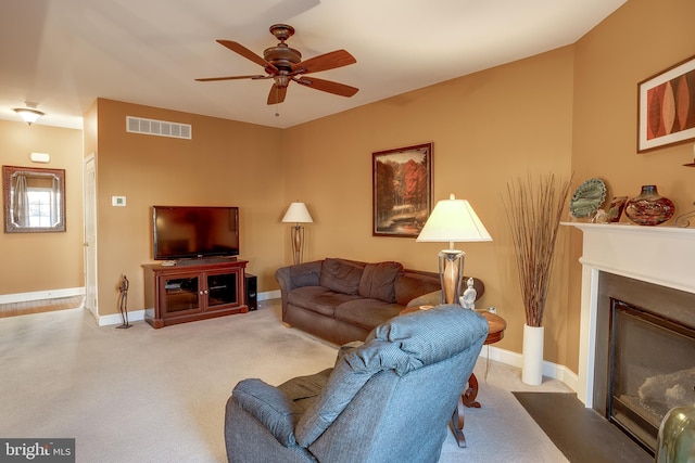 living room featuring light carpet, a fireplace with flush hearth, visible vents, and baseboards