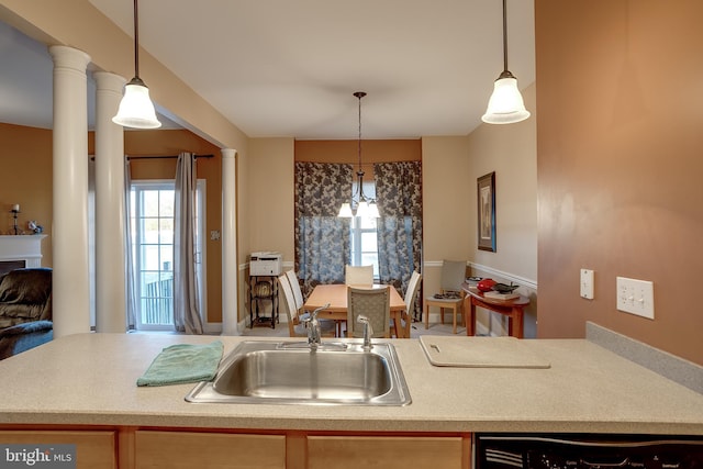 kitchen featuring decorative columns, pendant lighting, light countertops, and a sink