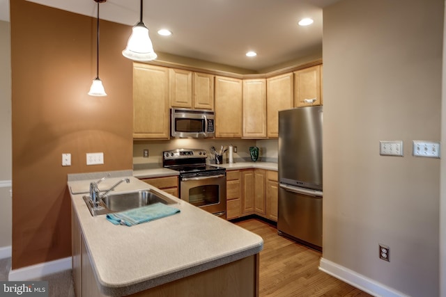 kitchen featuring appliances with stainless steel finishes, light countertops, a sink, and light brown cabinetry