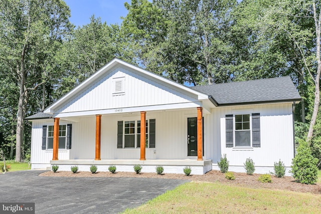 modern farmhouse featuring covered porch and roof with shingles