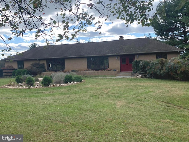 single story home featuring roof with shingles, a chimney, a front lawn, and brick siding