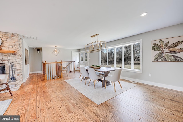 dining space with light wood-type flooring, an inviting chandelier, baseboards, and visible vents