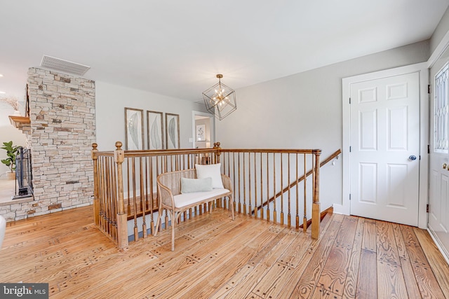 unfurnished room featuring a chandelier, visible vents, hardwood / wood-style floors, and an upstairs landing