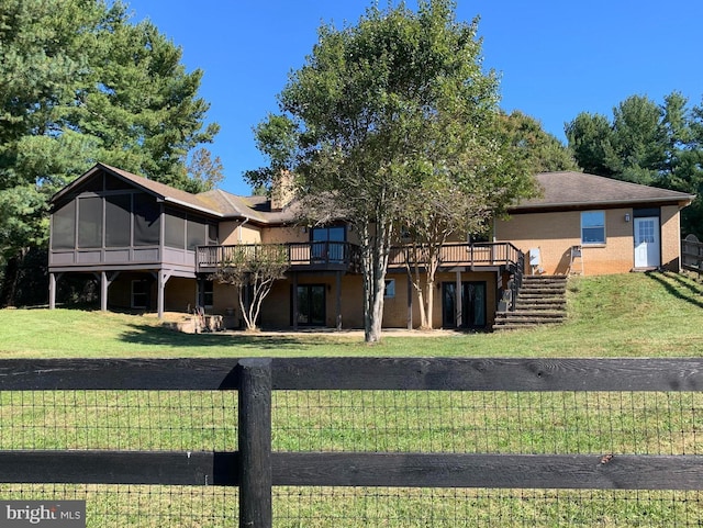 back of property featuring a deck, brick siding, a sunroom, stairway, and a lawn