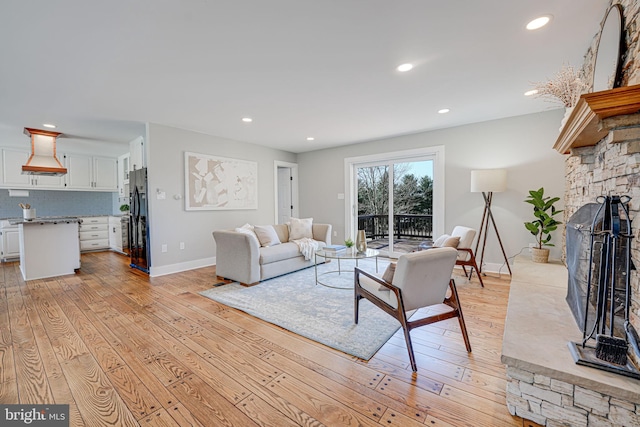 living room with light wood-style floors, a fireplace, baseboards, and recessed lighting