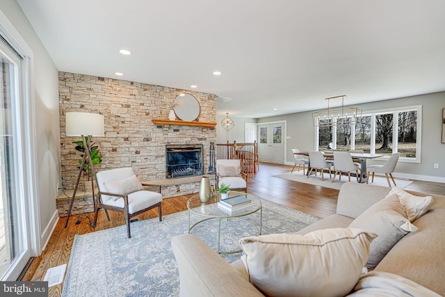 living area with recessed lighting, visible vents, a stone fireplace, wood finished floors, and baseboards