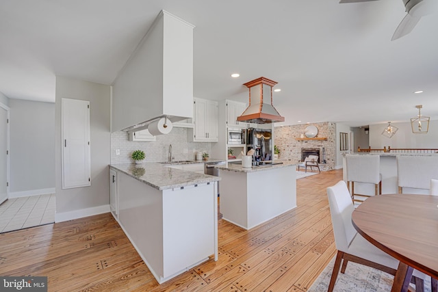 kitchen with tasteful backsplash, white cabinets, stainless steel microwave, freestanding refrigerator, and light wood-type flooring