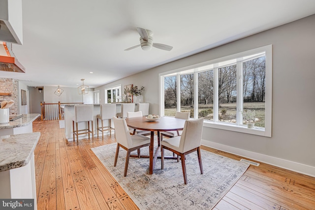 dining area featuring light wood-style floors, visible vents, baseboards, and a ceiling fan