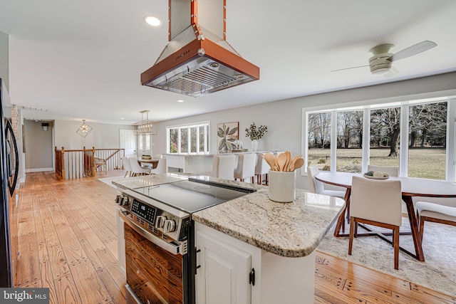 kitchen with a center island, light wood-style flooring, white cabinetry, light stone countertops, and stainless steel electric range