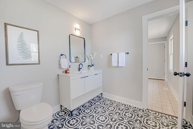 bathroom featuring toilet, tile patterned flooring, baseboards, and vanity