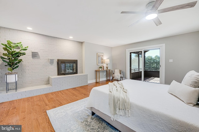 bedroom featuring baseboards, wood finished floors, access to exterior, a fireplace, and recessed lighting