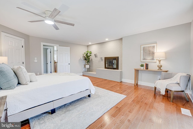 bedroom featuring ceiling fan, recessed lighting, a fireplace, baseboards, and light wood-style floors