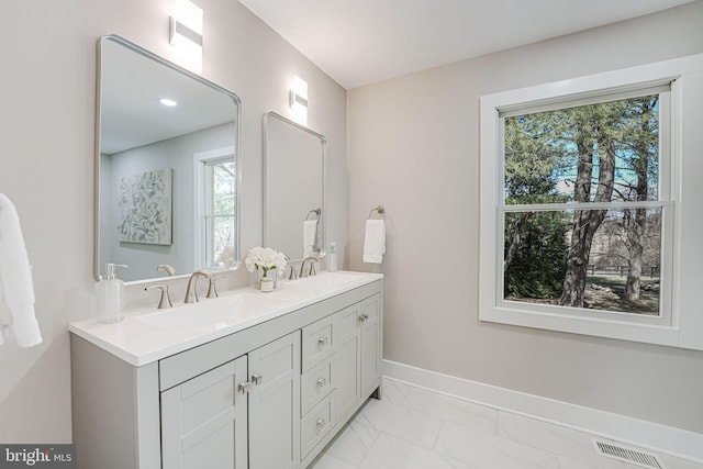 bathroom featuring a sink, visible vents, baseboards, marble finish floor, and double vanity