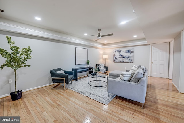 living room with a tray ceiling, light wood-style flooring, and recessed lighting