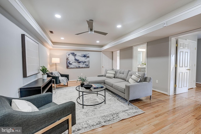 living area with recessed lighting, a raised ceiling, light wood-style flooring, and baseboards