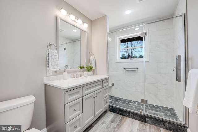 full bathroom with toilet, wood finished floors, a shower stall, and vanity